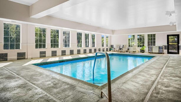 Una amplia piscina interior con vistas despejadas del entorno, incluyendo ventanas y una puerta.