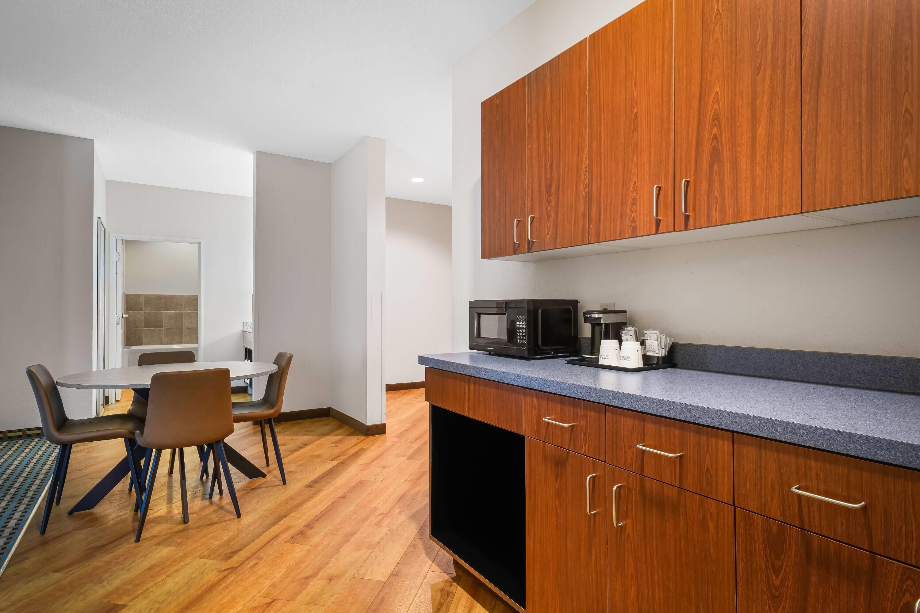 A modern kitchen with wooden cabinets, a microwave, and a coffee maker.
