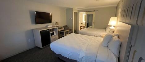 Une chambre d’hôtel avec deux lits, un bureau, une télévision et une petite kitchenette.