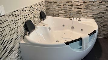 Une salle de bain moderne avec une baignoire sur pieds, des toilettes suspendues et un mur recouvert de carreaux.