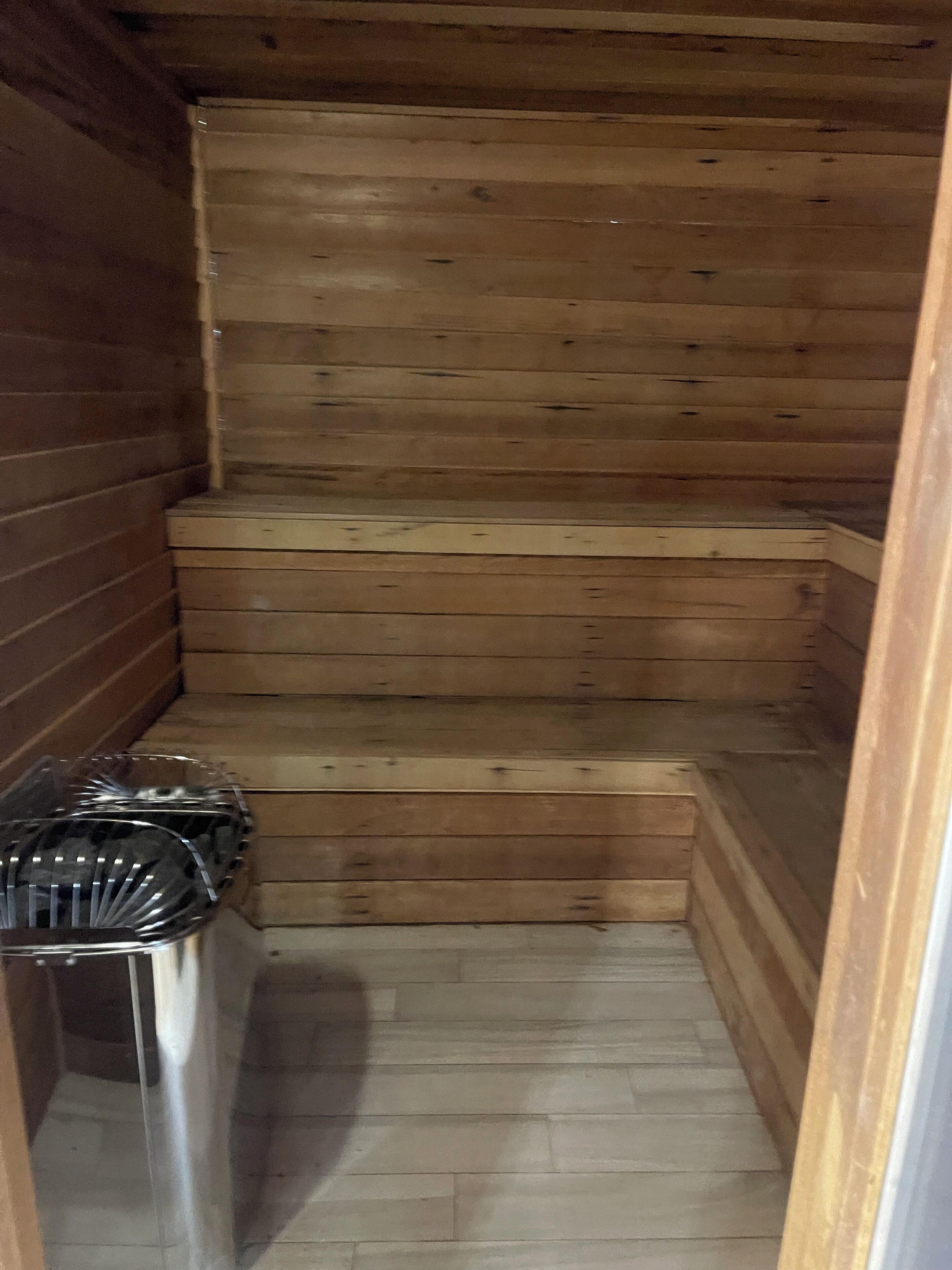 A wooden sauna with a bench and a glass container.