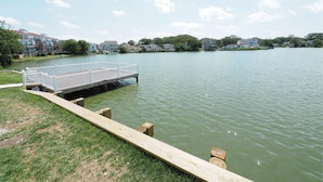 A lakeside dock with a wooden walkway leading to a white floating platform. - Seashire Inn & Suites (Virginia Beach)