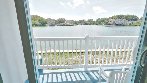 A balcony with a view of a lake and houses in the background. - Seashire Inn & Suites (Virginia Beach)
