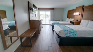 A hotel room with two beds, a wooden bench, a desk, a TV, and a balcony with a view. - Seashire Inn & Suites (Virginia Beach)