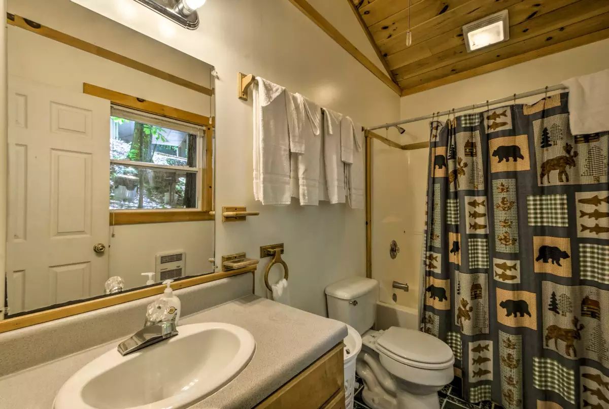 A bathroom with a sink, toilet, and shower curtain with animal prints.