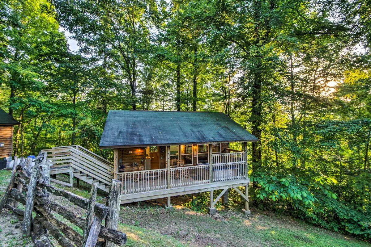 A wooden cabin with a balcony, surrounded by dense forest.
