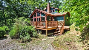 A cabin with a wooden deck, a chimney, and a small porch. - Nantahala Cabins (Bryson City)