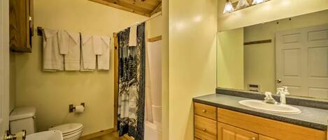 A bathroom with a wooden ceiling, a toilet, a sink, and a shower curtain.