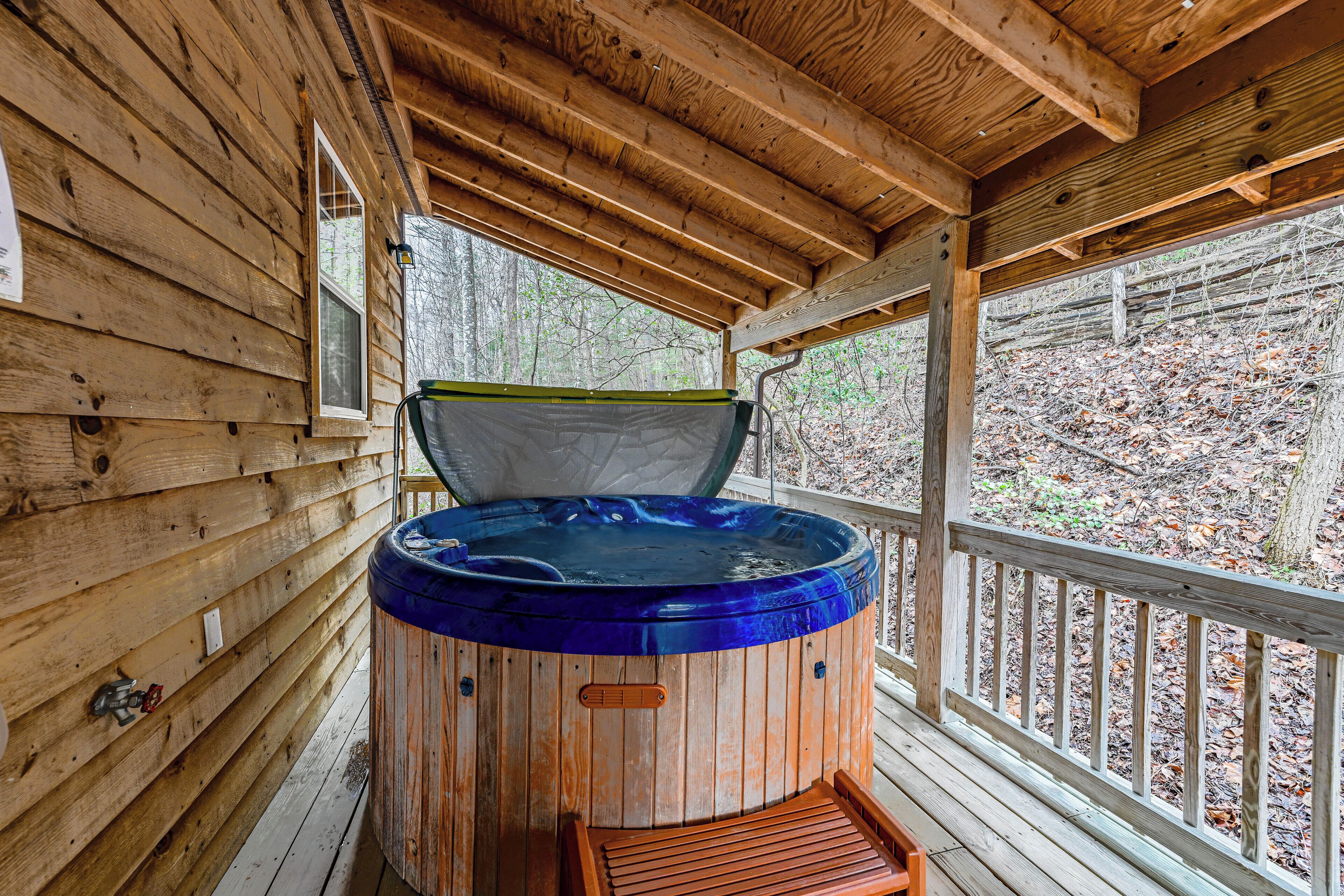 A wooden cabin with a hot tub on a porch.