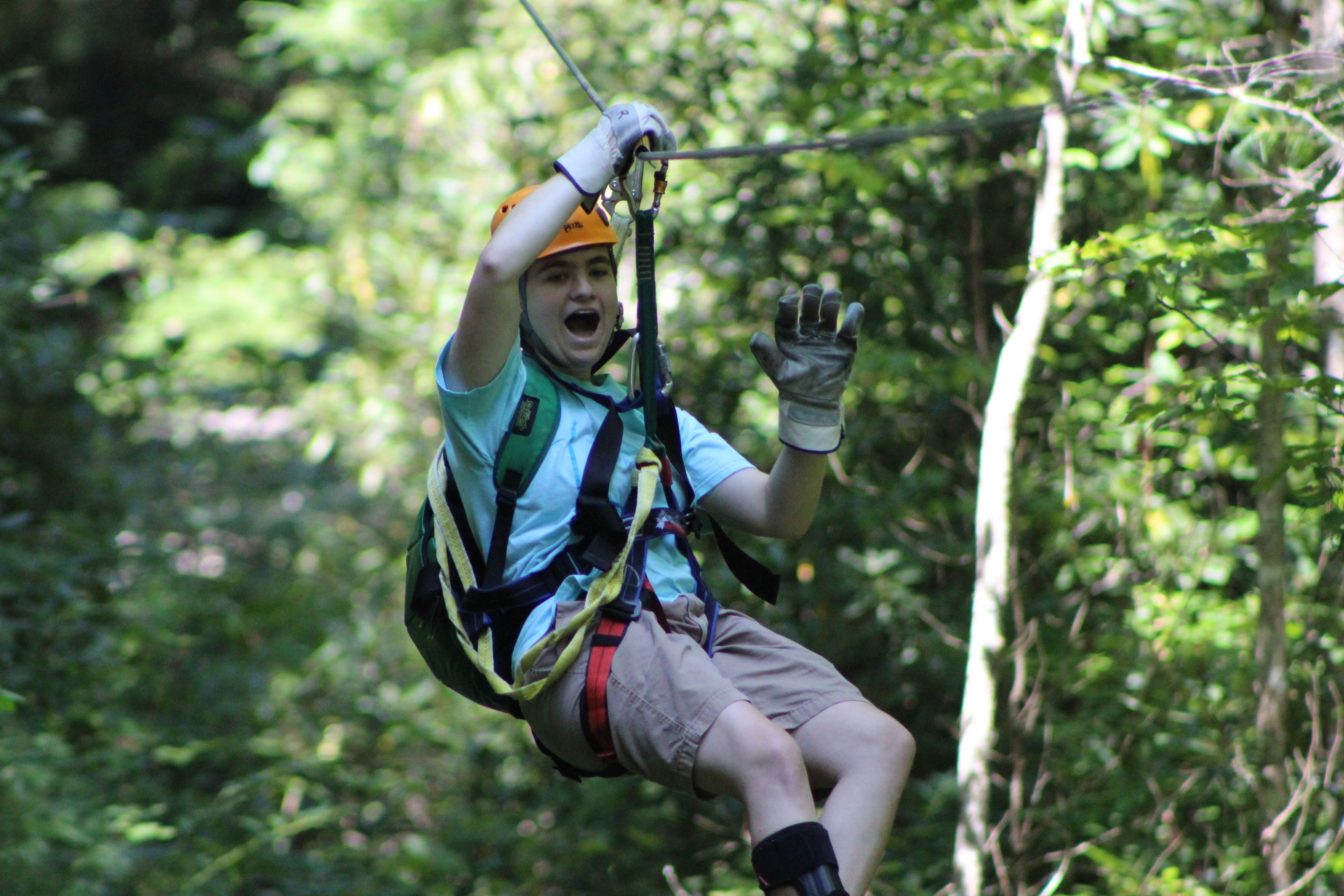 A person zip-lining through a forested area.