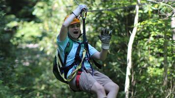 A person zip-lining through a forested area.