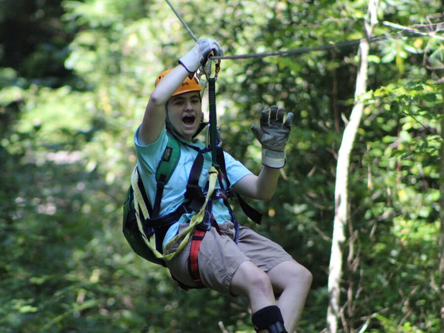 A person zip-lining through a forested area.