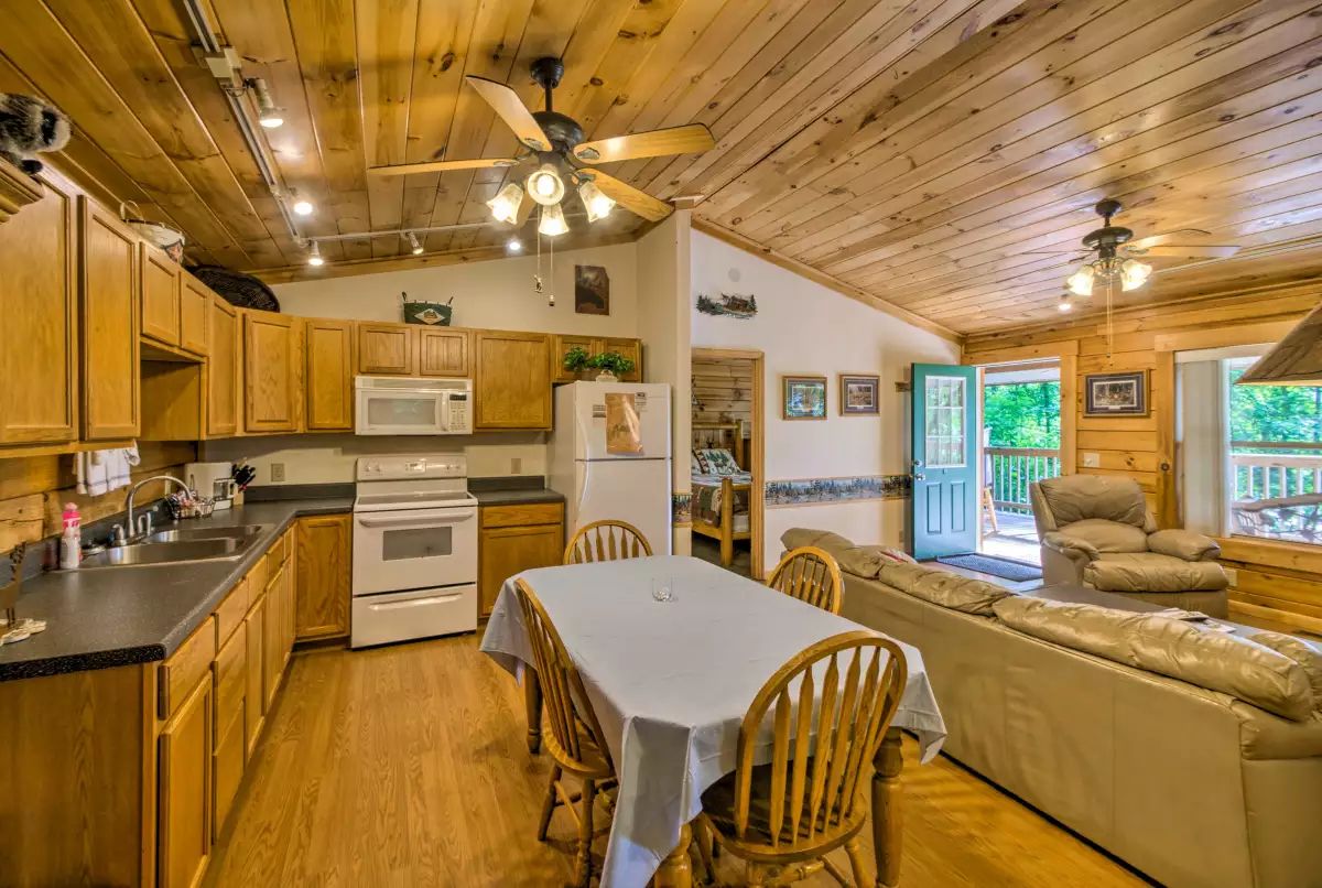 A wooden cabin with a kitchen, dining area, and a cozy seating area.