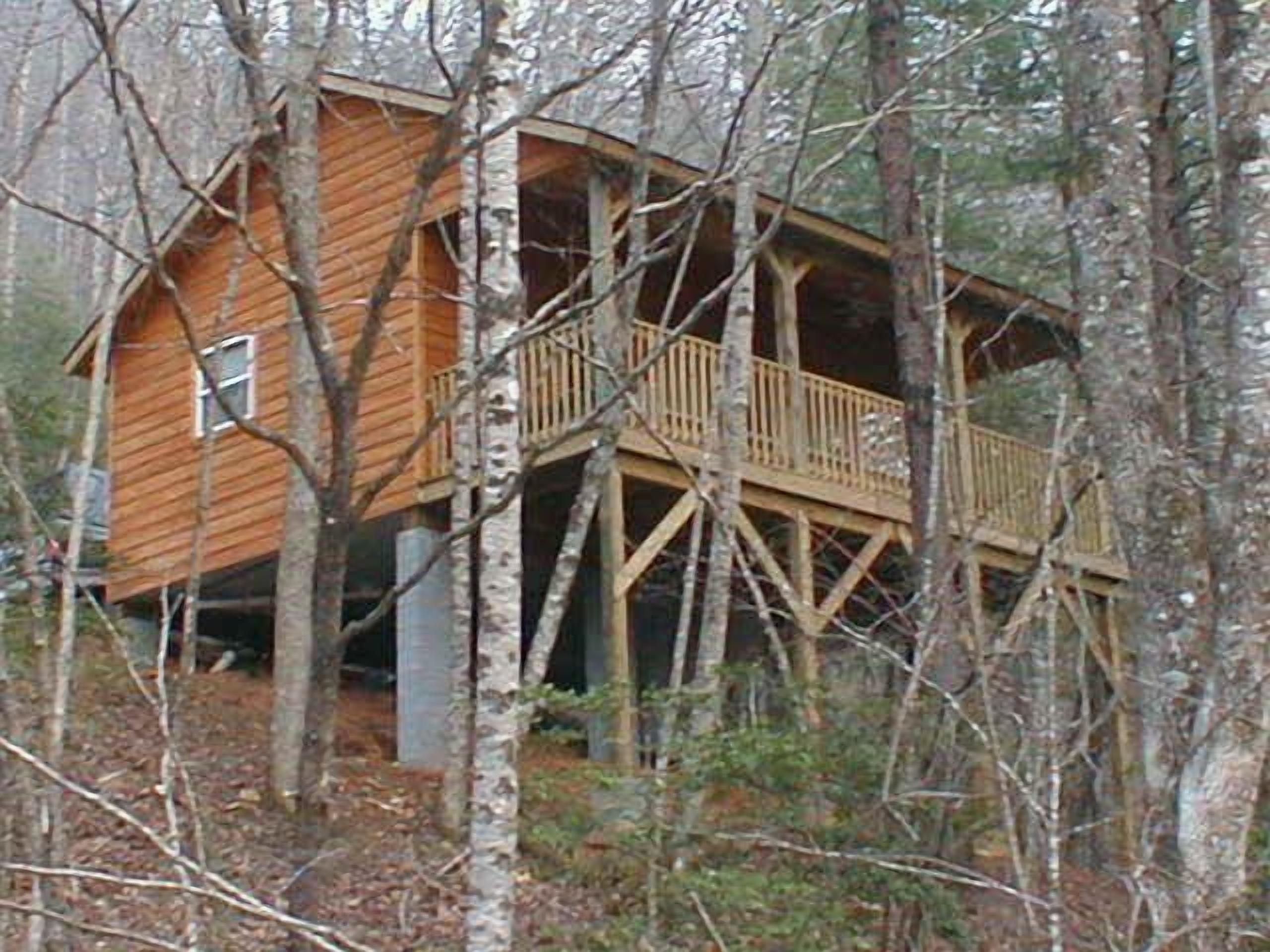 A wooden cabin with a balcony, surrounded by trees.