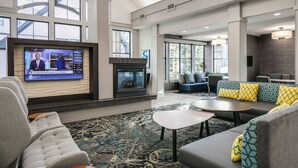A spacious lobby with a fireplace, comfortable seating, and large windows. - Residence Inn by Marriott Lincoln South (Lincoln)
