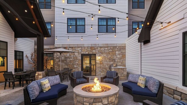 A courtyard with a stone fire pit, outdoor seating, and string lights. - Residence Inn by Marriott Lincoln South (Lincoln)