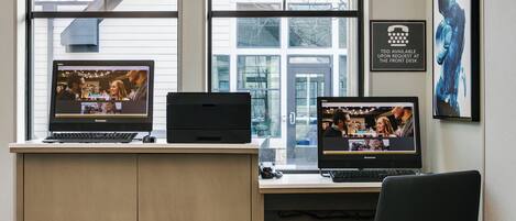 A workspace with two monitors, a printer, and a desk chair.