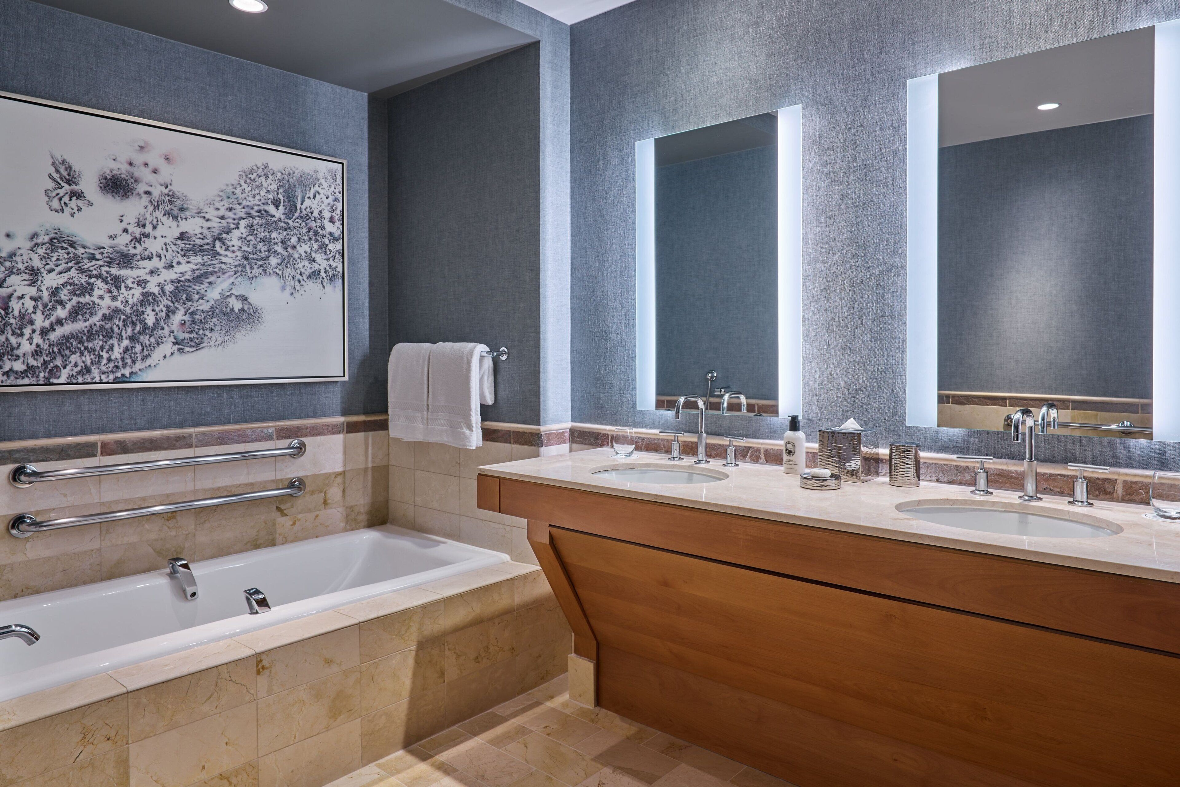 Ein modernes Badezimmer mit einer Badewanne, zwei Waschbecken und einem großen Spiegel.