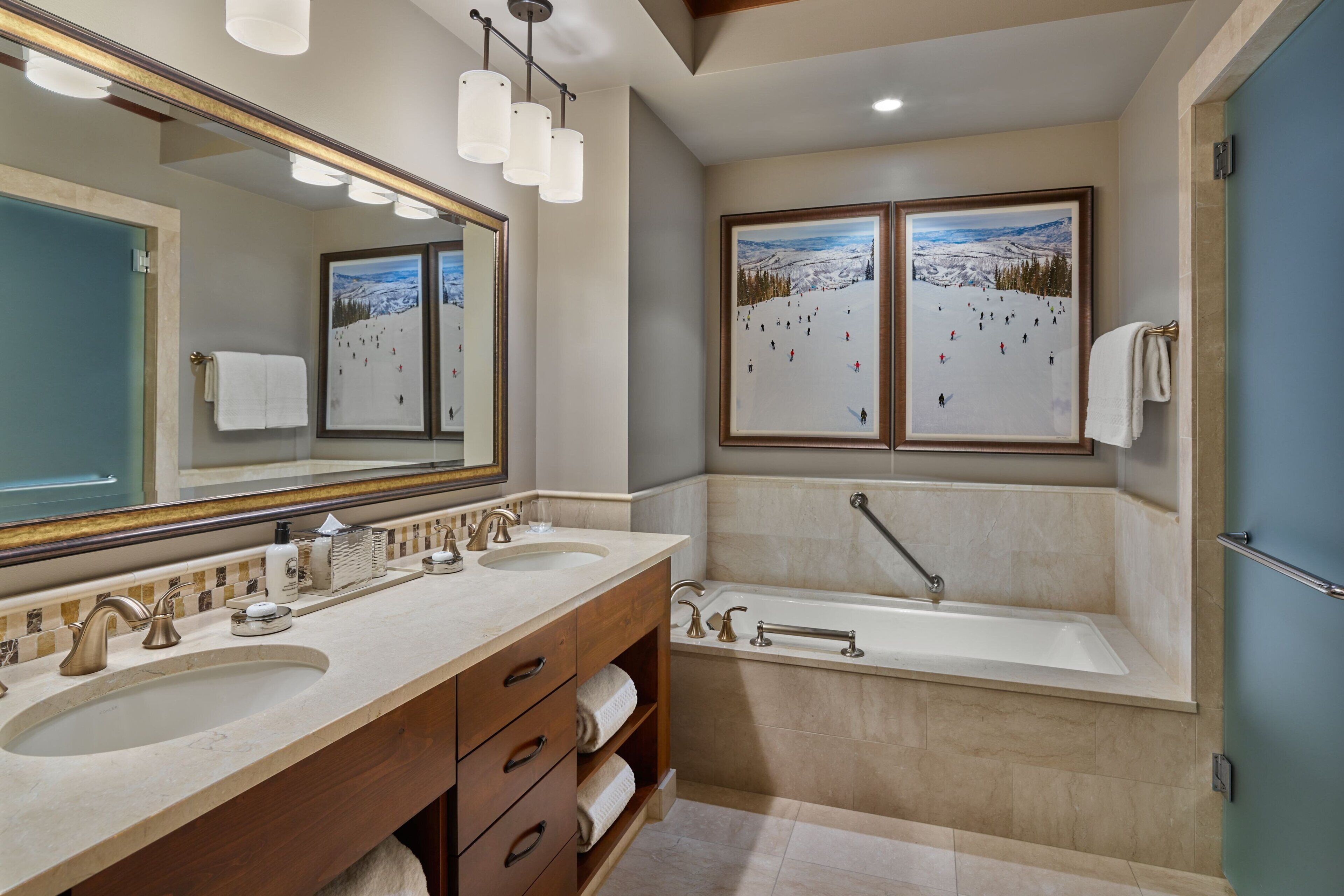 A bathroom with two sinks, a large mirror, and a bathtub.