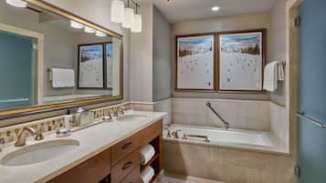 A bathroom with two sinks, a large mirror, and a bathtub.
