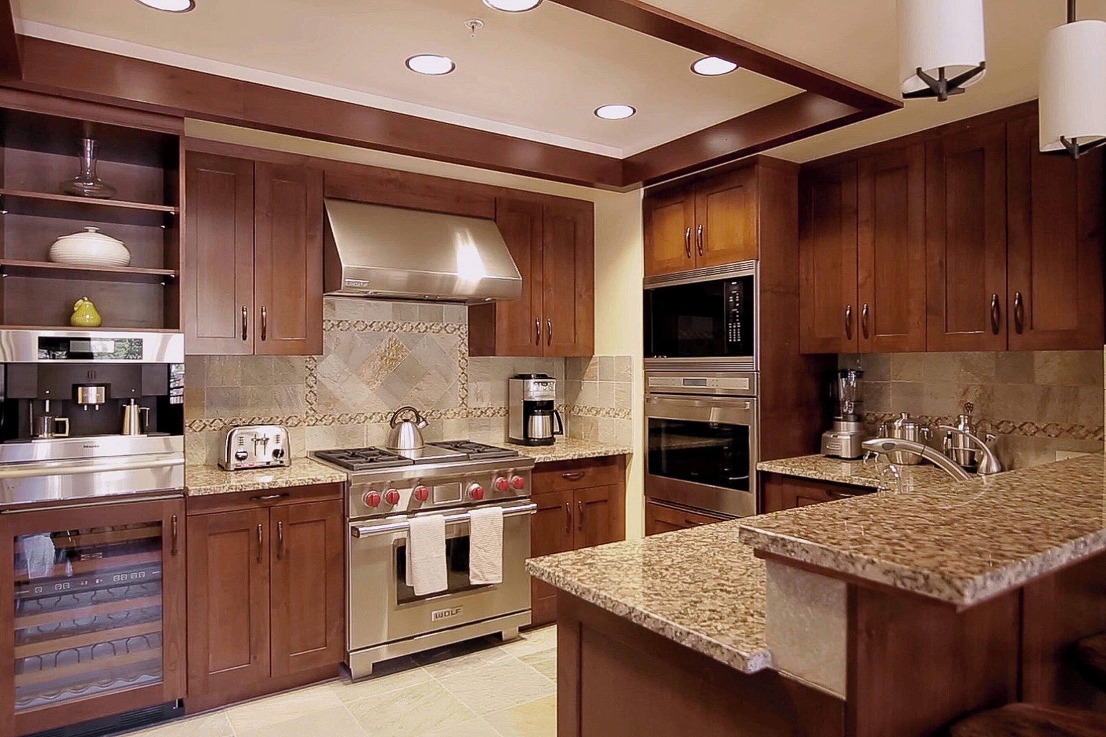 A modern kitchen with wooden cabinets, stainless steel appliances, granite countertops, and a built-in oven.