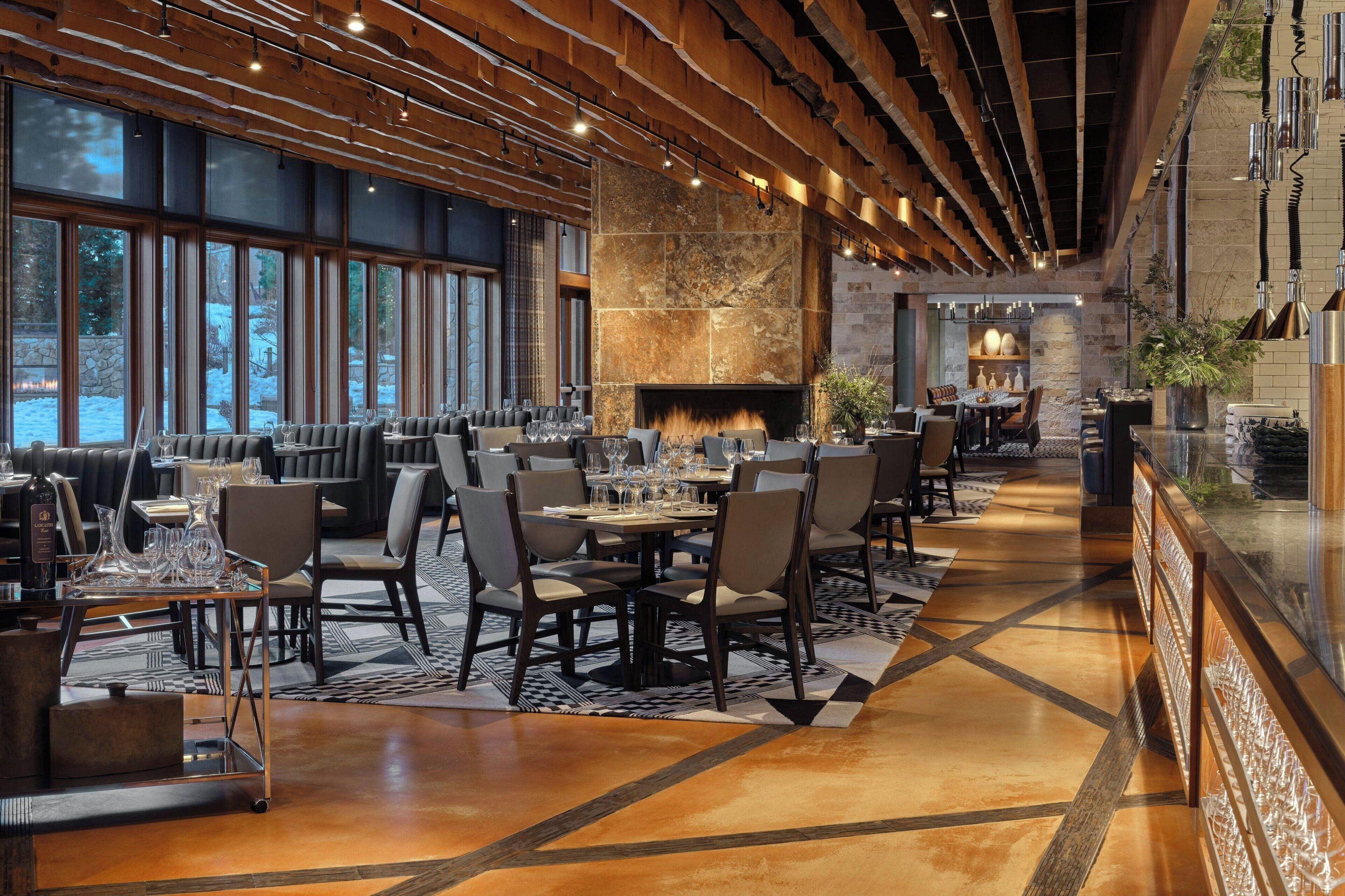 Un restaurant spacieux avec un long comptoir, de nombreuses tables et une grande cheminée en pierre.