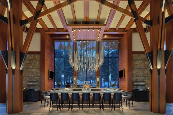 Un amplio bar con una barra larga, varios taburetes y un ventanal con vistas al exterior.