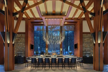 A grand staircase with wooden railings and stone walls, leading to a second-floor area with seating and a fireplace. at The Ritz-Carlton, Lake Tahoe