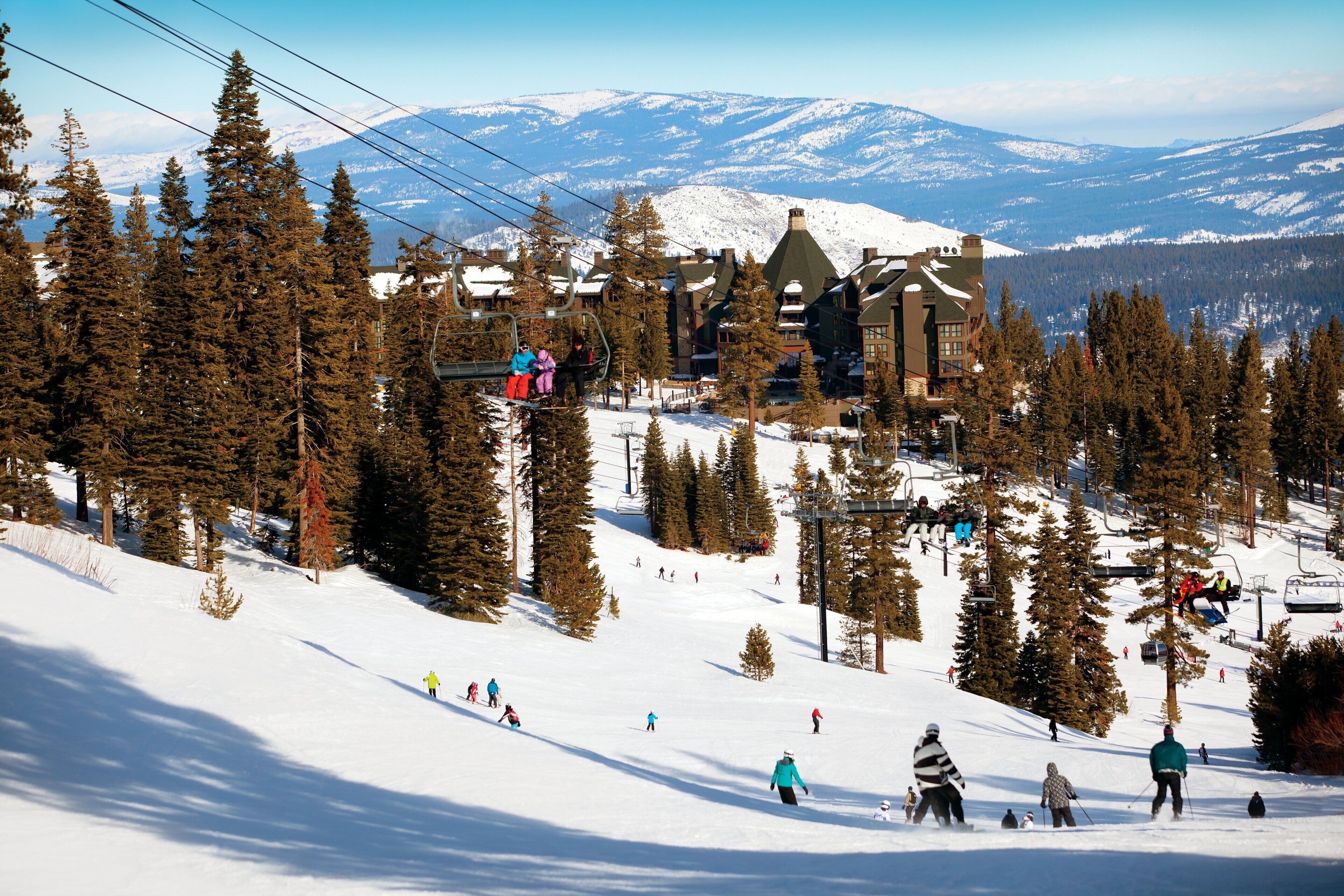 A ski resort with a lodge, ski lifts, and a mountainous backdrop.