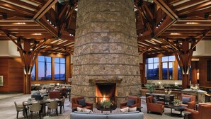 A spacious lobby with a stone fireplace, wooden beams, and comfortable seating areas. - The Ritz-Carlton, Lake Tahoe (Truckee)