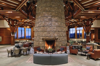 A large, multi-story lodge with a prominent tower and multiple balconies, surrounded by dense forest and hills. at The Ritz-Carlton, Lake Tahoe