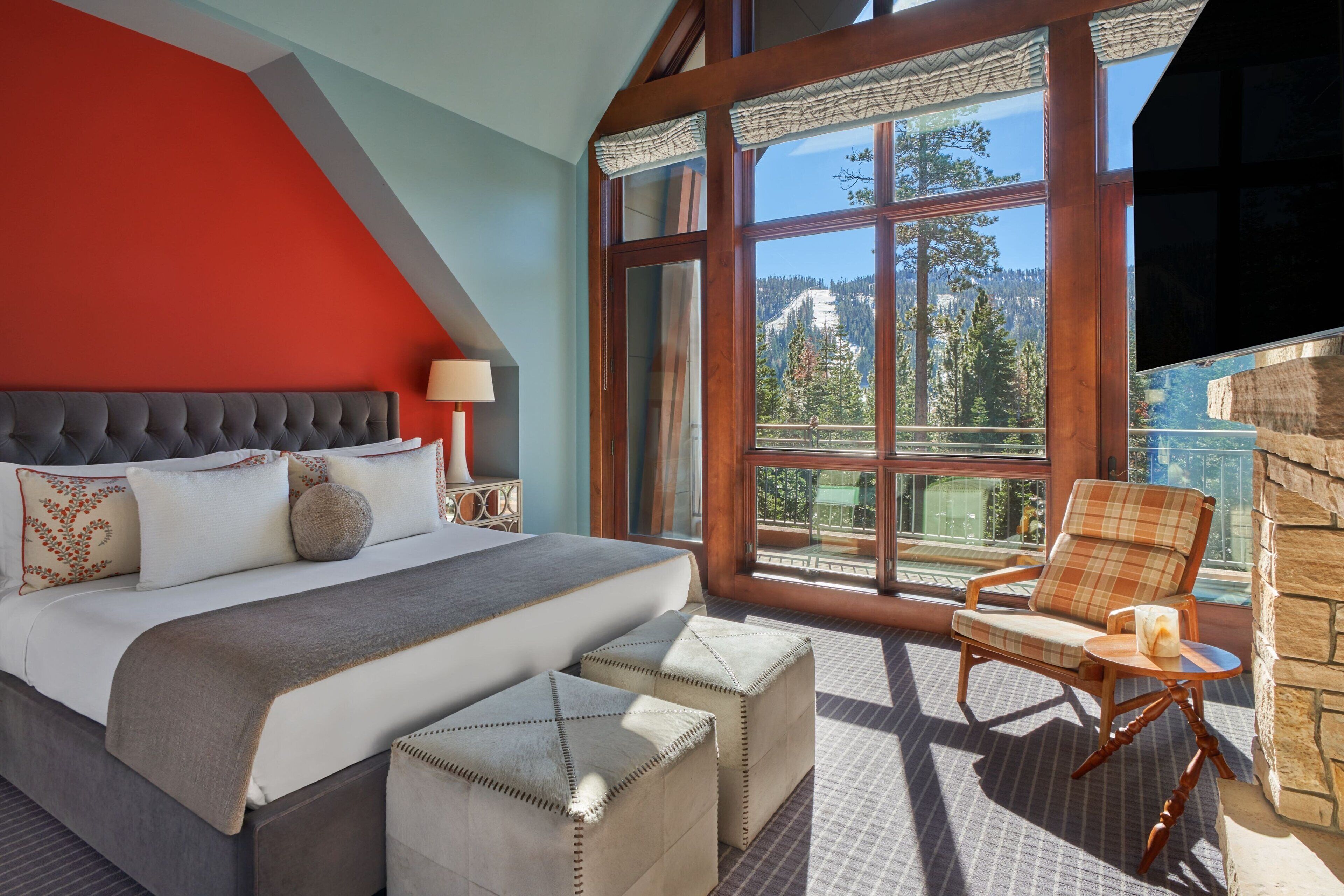 A bedroom with a large bed, a chair, and a view of a mountain.