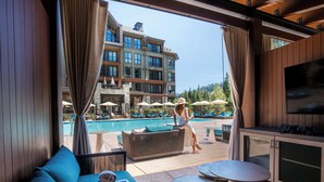 A poolside area with a sofa, a table, and a TV. - The Ritz-Carlton, Lake Tahoe (Truckee)