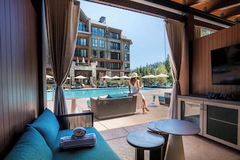 A spacious bar area with a long counter, multiple bar stools, and a large window offering a view of the outdoors. at The Ritz-Carlton, Lake Tahoe
