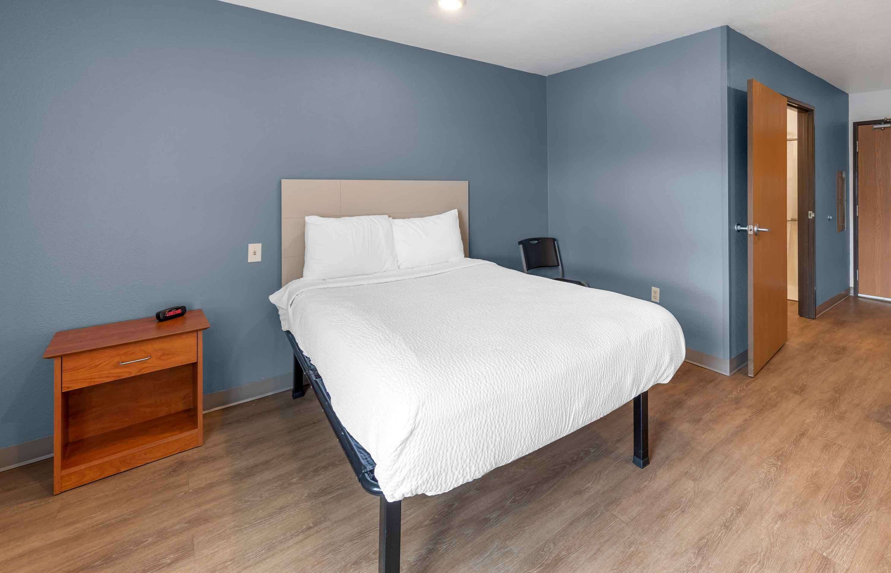 Une chambre à coucher bien rangée, avec un lit, une table de chevet et une chaise.