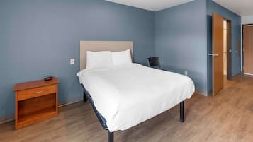 Une chambre à coucher bien rangée, avec un lit, une table de chevet et une chaise.