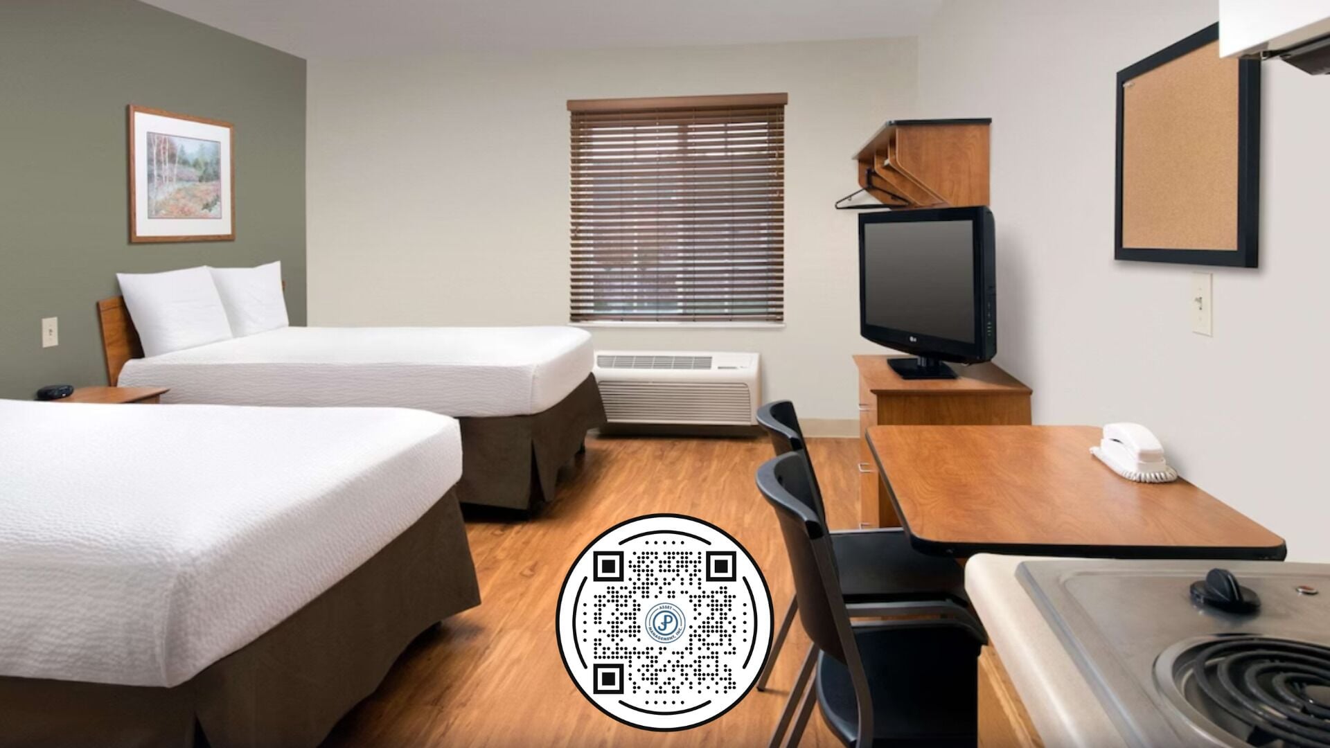 A hotel room with two beds, a desk, a television, a small table, a chair, a sink, and a window with blinds.