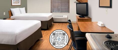 A hotel room with two beds, a desk, a television, a small table, a chair, a sink, and a window with blinds.
