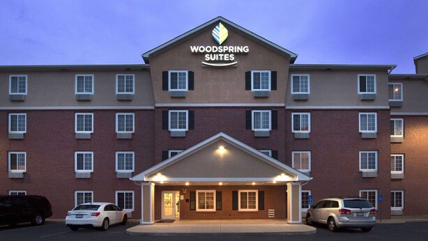Un hôtel à plusieurs étages, reconnaissable à son enseigne bien visible indiquant « Woodspring Suites ».