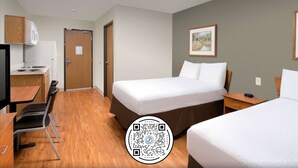 Une chambre d’hôtel avec un lit, un bureau, une chaise, un four à micro-ondes et un tableau au mur.