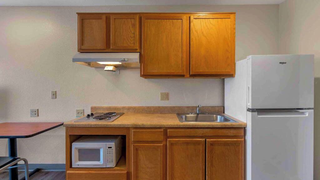 A compact kitchen with wooden cabinets, a microwave, a sink, and a refrigerator.