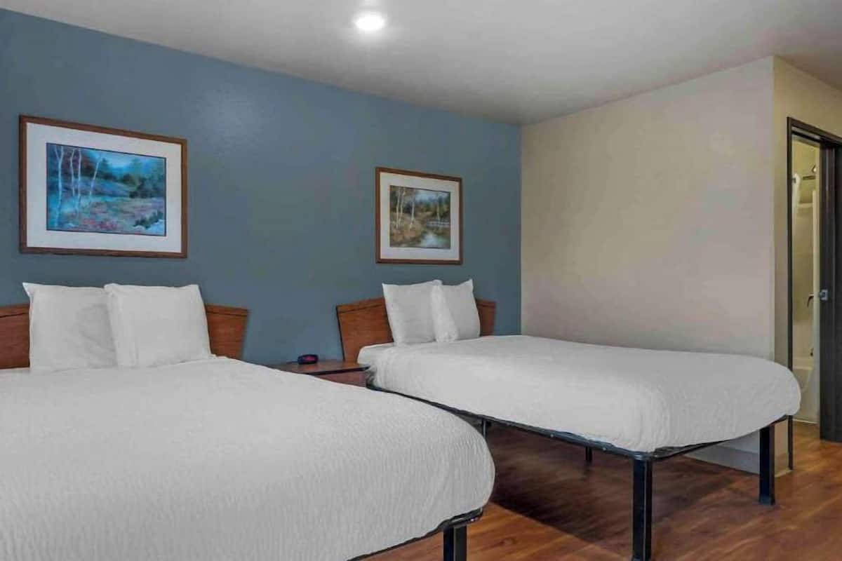 Dos camas individuales con cabeceros de madera en una habitación con paredes azules y suelo de madera.