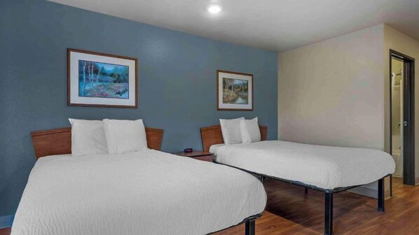 Two single beds with wooden headboards in a room with blue walls and wooden flooring.