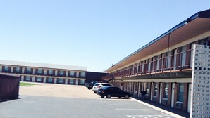 A parking lot with a building that has a flat roof and large windows. - Budget Host Platte Valley Inn (Julesburg)