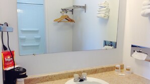 A bathroom with a sink, a mirror, a towel rack, and a coffee maker. - Budget Host Platte Valley Inn (Julesburg)