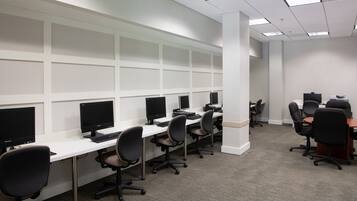 Une salle informatique dotée de plusieurs postes de travail, chacun étant équipé d’un écran, d’un clavier et d’une chaise.