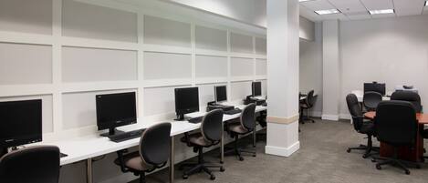 A computer lab with multiple workstations, each equipped with a monitor, keyboard, and chair.