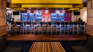 Zona de bar con varias botellas de licor, taburetes y una barra.