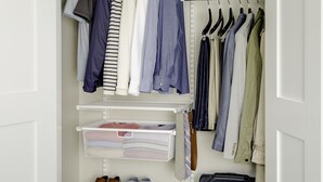 Un vestidor amplio con ropa colgada, estantes y una maleta.