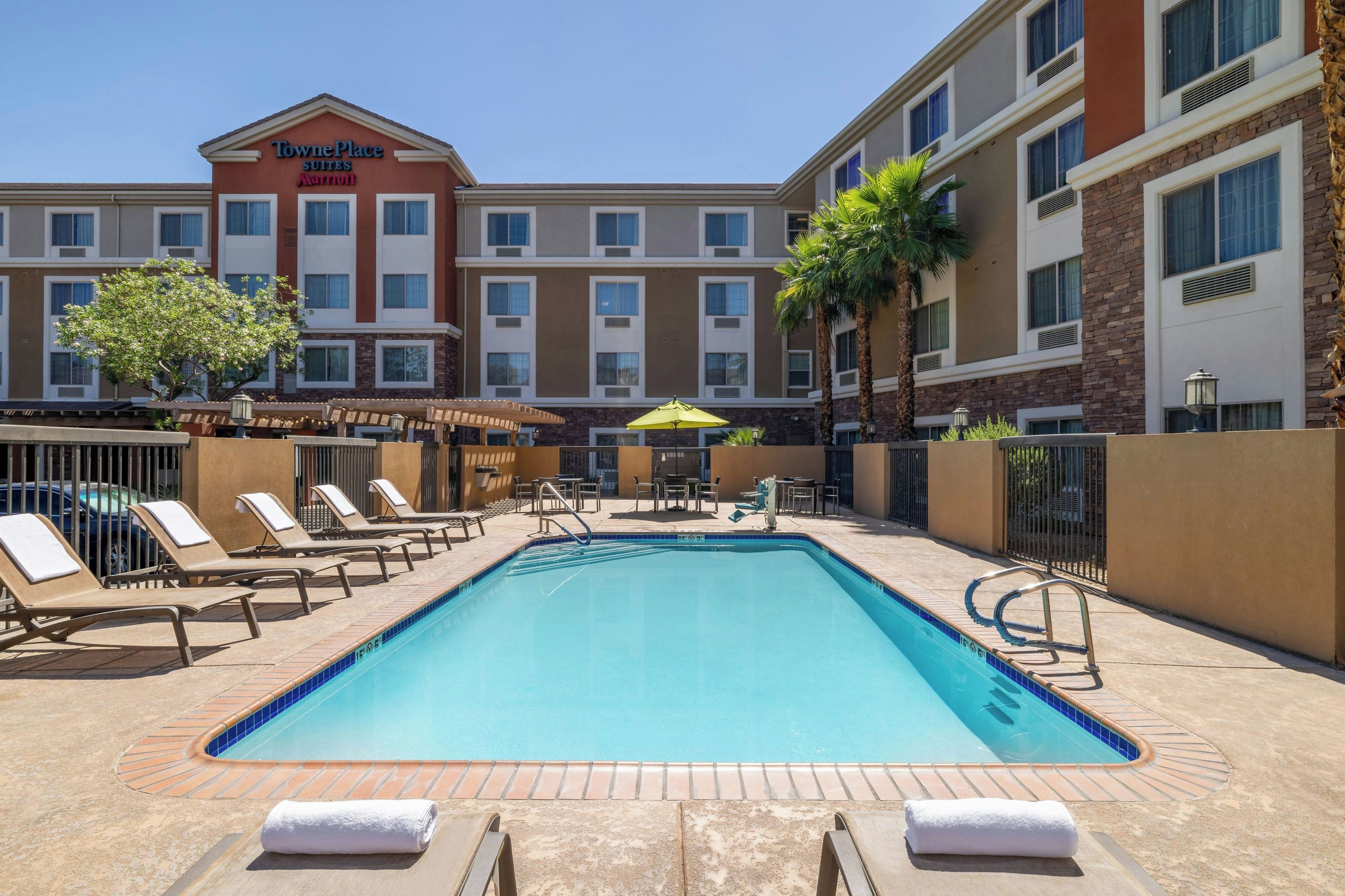 A hotel pool area with lounge chairs, a swimming pool, and a Marriott TownePlace Suites building in the background.